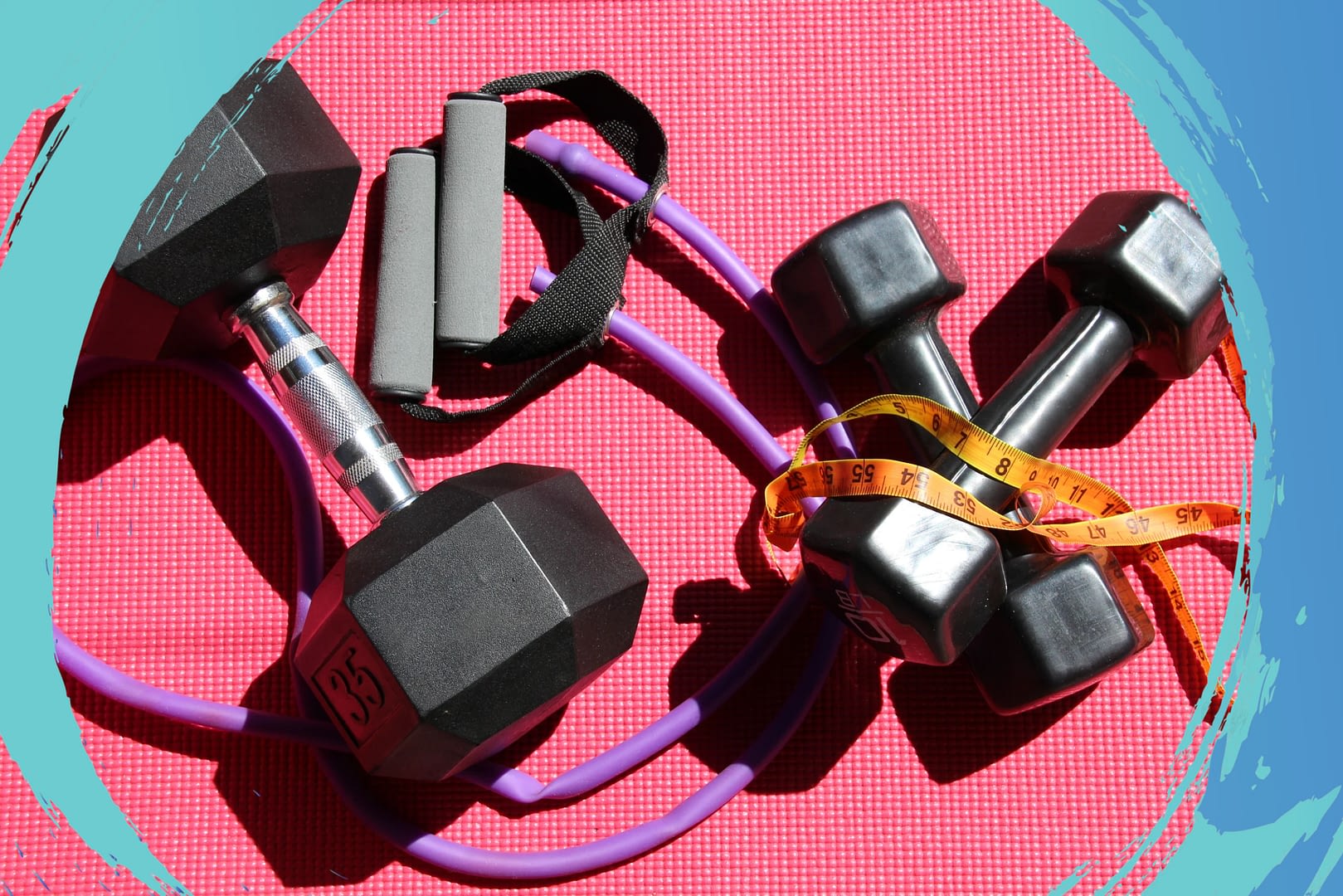 Dumbbells, jump rope, and a measuring tape on top of a pink yoga mat.